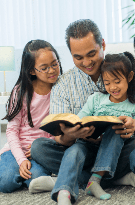 asian father with two daughters reading the bible